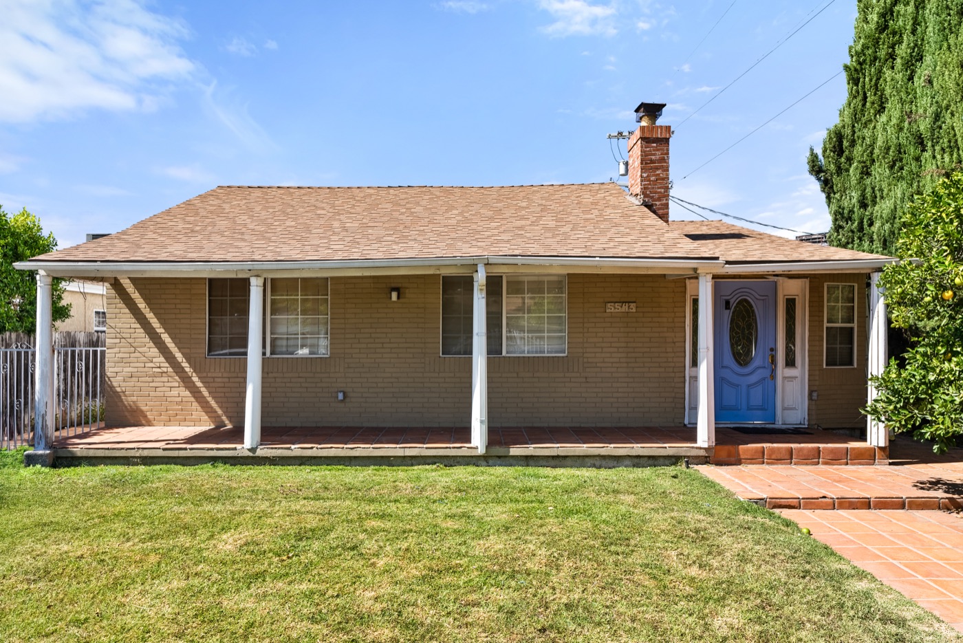 The front of 5543 Buffalo Avenue in Sherman Oaks, a single-story 1941 house with a covered porch, brick chimney and lawn